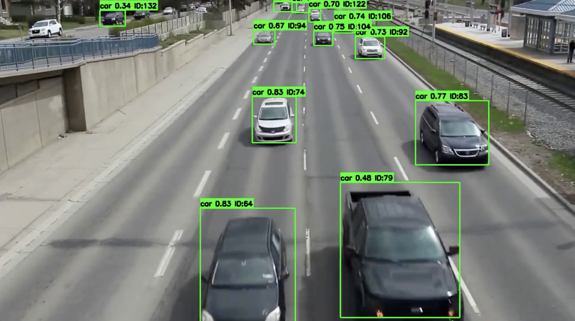 Aerial traffic footage with AI detections tracking vehicles through a city corridor.